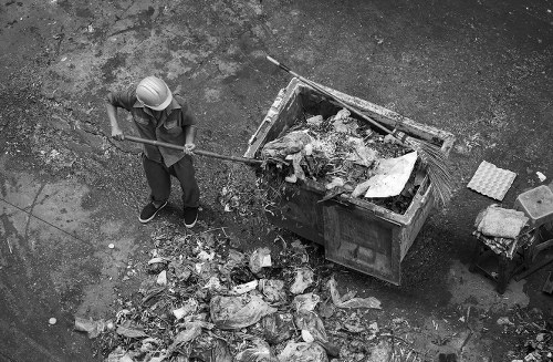 Construction workers unloading materials into a builders skip in Catford